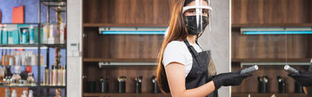 young hairdresser in face shield and latex gloves holding comb while looking at camera, banner