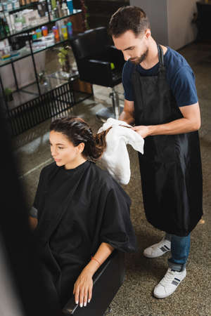 high angle view of barber wiping hair of woman with towel, blurred foreground