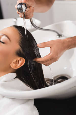 cropped view of hairdresser washing hair of client in beauty salonの写真素材