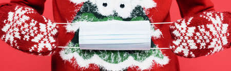 Cropped view of man in mittens holding medical mask isolated on red, banner