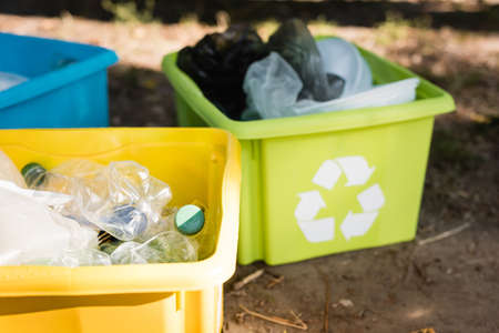 containers with recycling emblems, full of plastic waste on blurred background, ecology concept
