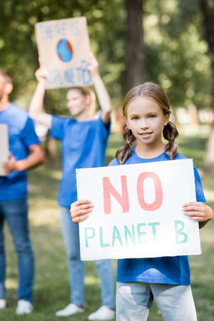 girl holding placard with no planet b inscription near family with posters on blurred background, ecology conceptの写真素材