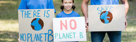 family of volunteers holding placards with globe, save, and no planet b inscription, ecology...