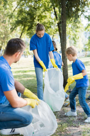 family of activists collecting waste in recycled plastic bags, ecology concept