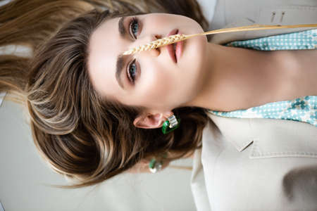 top view of barley spikelet on face of young model lying on white