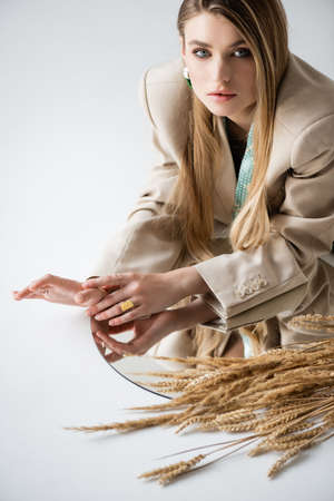 model looking at camera near wheat spikelets and mirror on whiteの写真素材