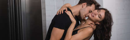 Passionate man hugging and leaning with seductive woman with closed eyes near elevator, banner