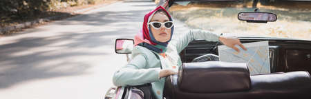Elegant woman holding map on driver seat of vintage auto, banner