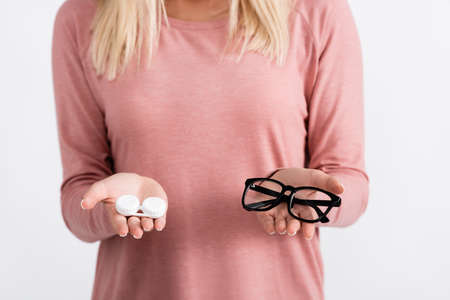 Cropped view of woman holding box with contact lenses and eyeglasses isolated on grayの写真素材