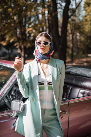 Fashionable woman in sunglasses standing near cabriolet car outdoorsの写真素材