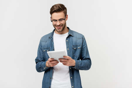 Smiling man in eyeglasses holding digital tablet isolated on gray