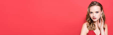 young woman in earrings looking at camera on red, bannerの写真素材