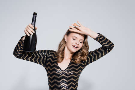 cheerful woman holding bottle with champagne on grayの写真素材