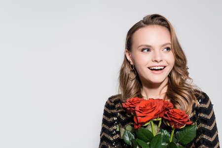 excited young woman holding bouquet of red roses isolated on grayの写真素材