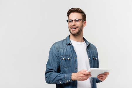 Smiling man in eyeglasses holding digital tablet isolated on gray