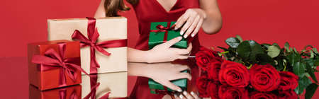 cropped view of holding present near roses on red, bannerの写真素材