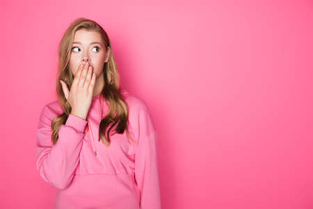 shocked beautiful woman covering mouth on pink backgroundの写真素材