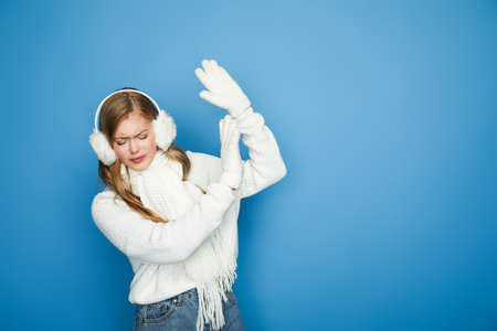 beautiful woman in winter white outfit showing stop gesture isolated on blueの写真素材