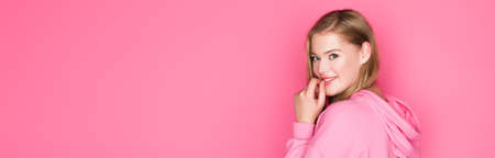 pretty young woman in hoodie smiling on pink background, bannerの写真素材