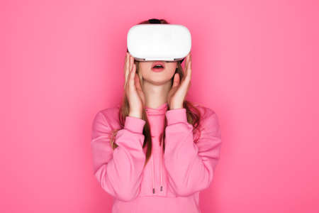 shocked beautiful woman in vr headset on pink backgroundの写真素材