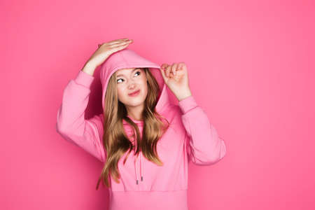 beautiful young woman in hoodie on pink backgroundの写真素材