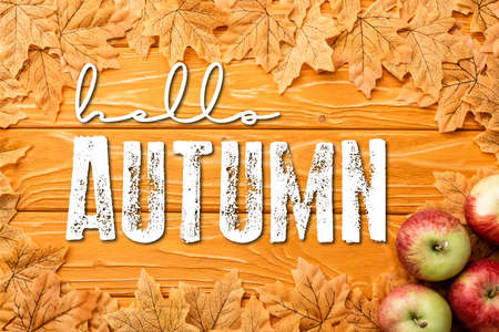 top view of ripe apples and leaves near hello autumn lettering on wooden background