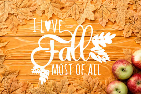 top view of ripe apples and autumnal foliage near i love fall most of all lettering on wooden...
