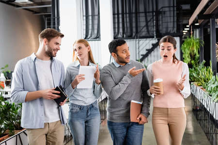 Multicultural businesspeople with digital tablet and coffee to go talking in office