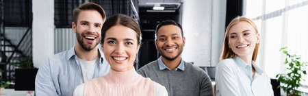 Multiethnic businesspeople smiling at camera in office, banner