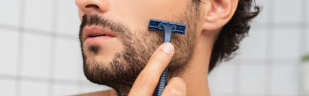 Cropped view of bearded man shaving with razor, bannerの写真素材