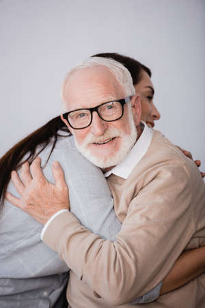 smiling aged man looking at camera while hugging adult daughter at homeの写真素材