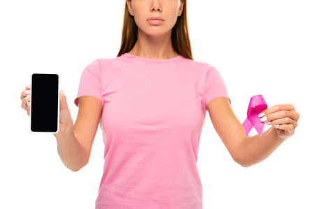 Cropped view of smartphone with blank screen and ribbon of breast cancer awareness in hands of woman on blurred background isolated on whiteの写真素材