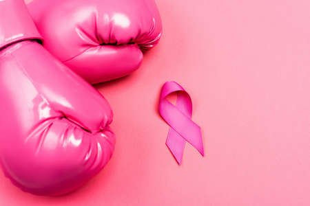 Top view of boxing gloves and ribbon of breast cancer awareness on pink surfaceの写真素材