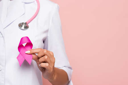 Cropped view of doctor holding pink symbol of breast cancer awareness isolated on pinkの写真素材