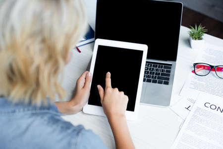 back view of woman pointing with finger at digital tabletの写真素材
