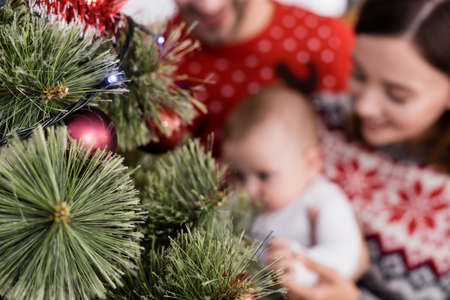 decorated Christmas tree near blurred family on background