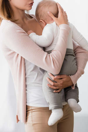 cropped view of mother holding in arms while calming infant sonの写真素材