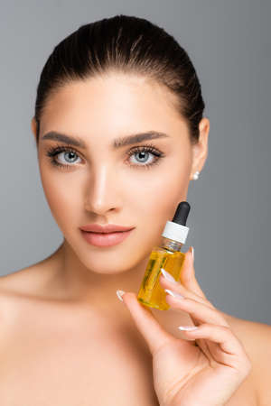 woman holding bottle with serum isolated on gray