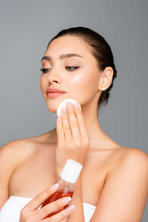 beautiful woman with cotton pad and lotion isolated on grayの写真素材