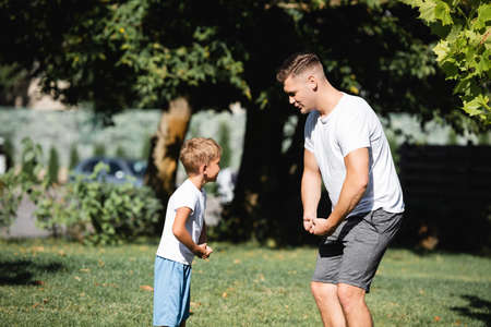 Son and father in sportswear showing muscles in park on blurred backgroundの写真素材