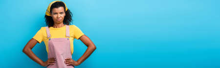 displeased african american woman standing with hands on hips on blue, banner