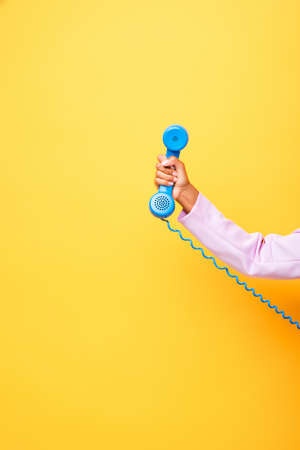 cropped view of african american woman holding blue retro phone on yellowの写真素材