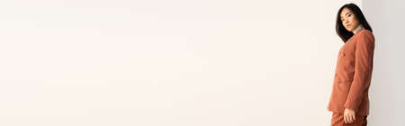 brunette asian woman in trendy suit posing on white, bannerの写真素材