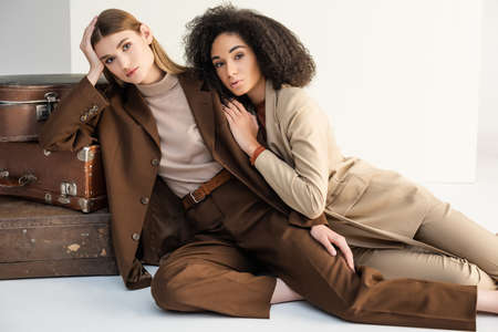 young model and african american woman posing near suitcases on whiteの写真素材