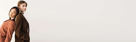 young stylish model posing with brunette asian friend on white, bannerの写真素材