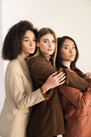 stylish interracial models in suits hugging while posing on whiteの写真素材