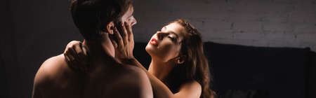 Sensual woman with red lips hugging shirtless man at home, bannerの写真素材