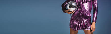 cropped view of elegant woman in sequin dress with disco ball on blue background, bannerの写真素材