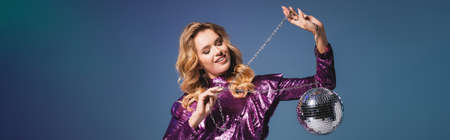 happy elegant woman in sequin dress with disco ball on blue background, bannerの写真素材