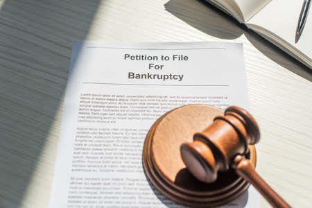 Gavel with wooden block on petition for bankruptcy near blank notebook on white textured backgroundの写真素材